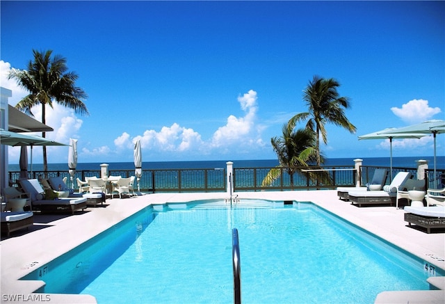 view of swimming pool with a water view and a patio