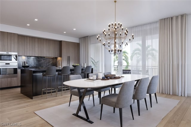 dining area with a notable chandelier, sink, and light hardwood / wood-style floors