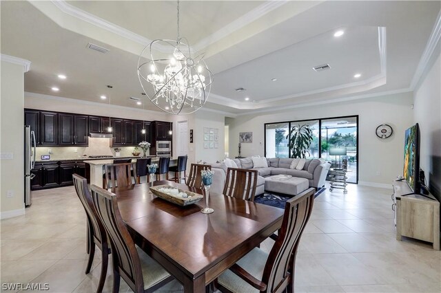 dining space with an inviting chandelier, ornamental molding, a tray ceiling, and light tile floors