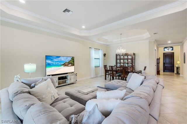 tiled living room featuring a notable chandelier, a tray ceiling, and crown molding