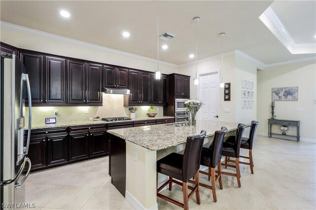 kitchen featuring a kitchen breakfast bar, crown molding, light stone countertops, an island with sink, and appliances with stainless steel finishes