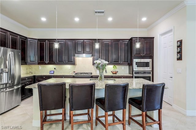 kitchen featuring pendant lighting, appliances with stainless steel finishes, a kitchen bar, and a center island with sink