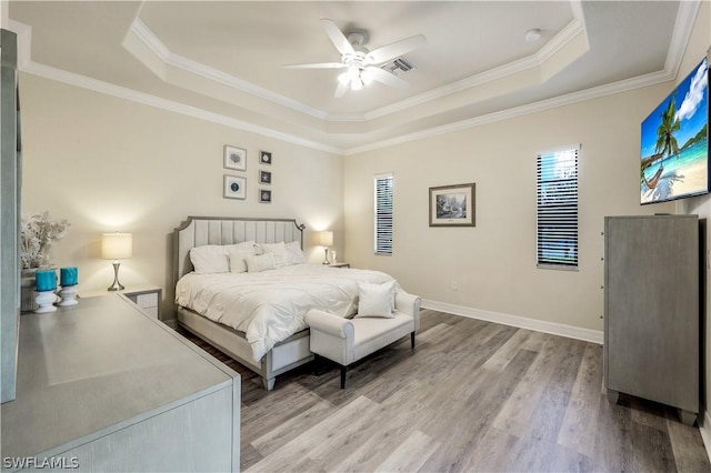 bedroom with crown molding, ceiling fan, a raised ceiling, and light hardwood / wood-style floors