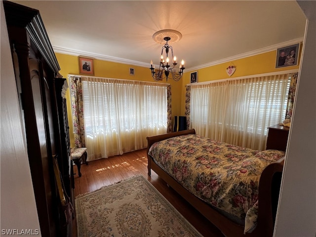 bedroom featuring a notable chandelier, ornamental molding, and hardwood / wood-style flooring