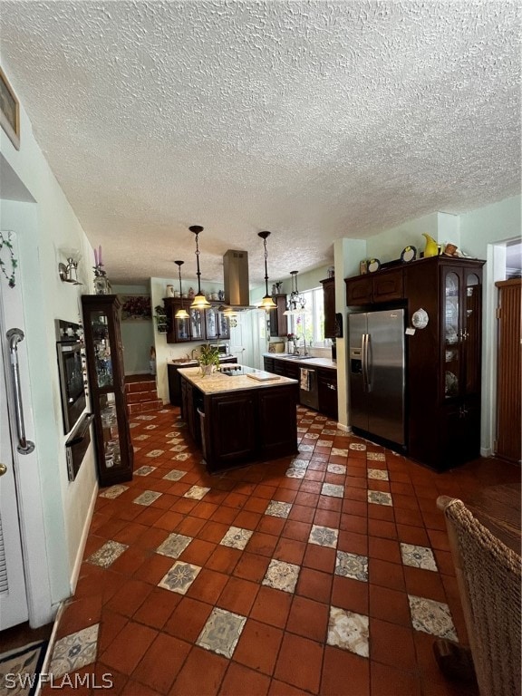 kitchen featuring dark brown cabinetry, a kitchen island, stainless steel appliances, tile flooring, and a textured ceiling