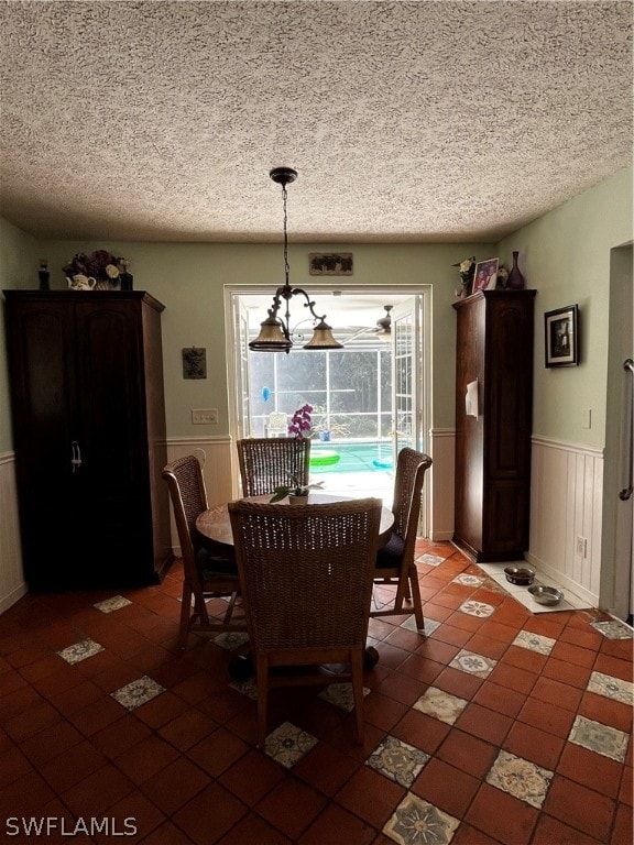 tiled dining space featuring a chandelier and a textured ceiling