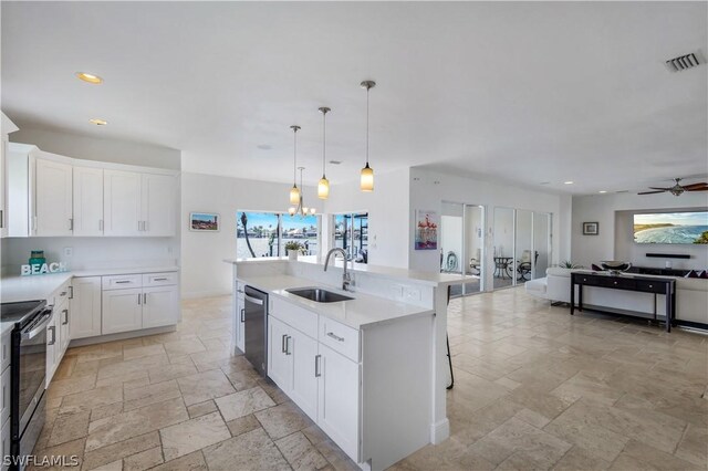 kitchen with stainless steel appliances, a kitchen island with sink, sink, white cabinetry, and hanging light fixtures