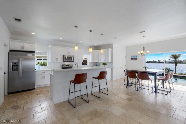 kitchen with white cabinetry, pendant lighting, a kitchen island with sink, and appliances with stainless steel finishes