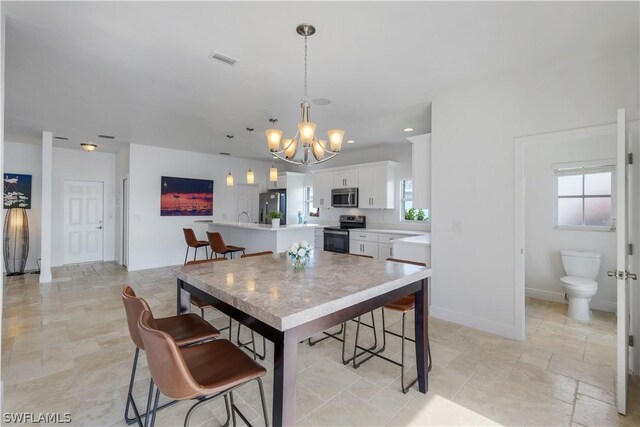 dining space featuring sink and an inviting chandelier