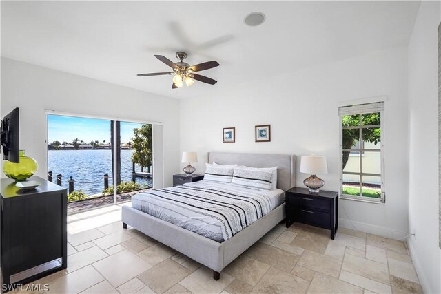 bedroom featuring multiple windows, access to outside, a water view, and ceiling fan