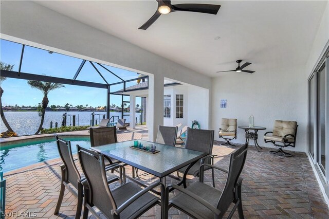 view of patio with a water view, glass enclosure, and ceiling fan