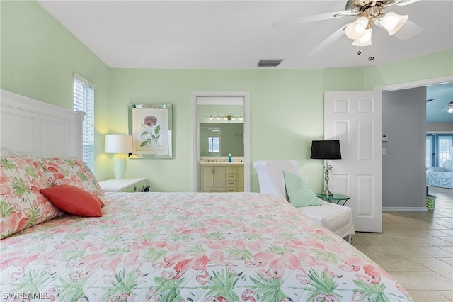 bedroom with multiple windows, ceiling fan, light tile patterned flooring, and ensuite bathroom