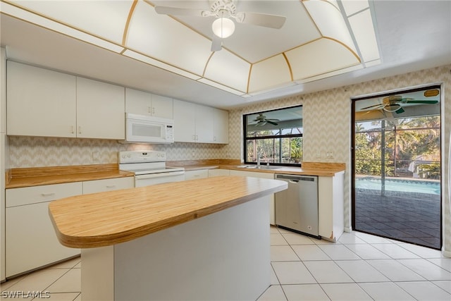 kitchen with a center island, white appliances, white cabinets, sink, and butcher block countertops