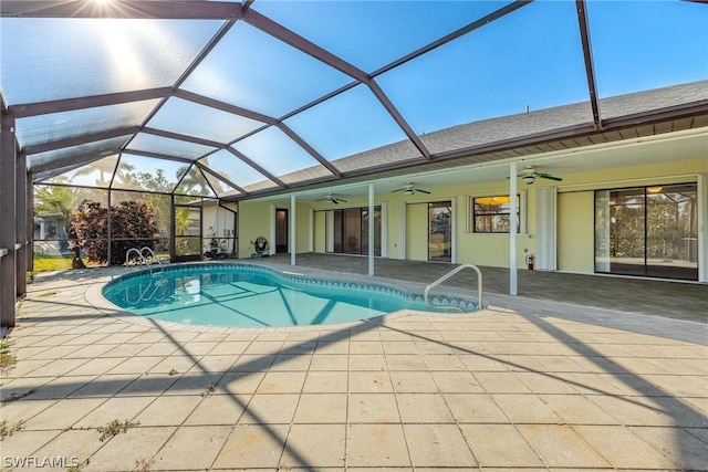 view of swimming pool featuring glass enclosure, ceiling fan, and a patio area