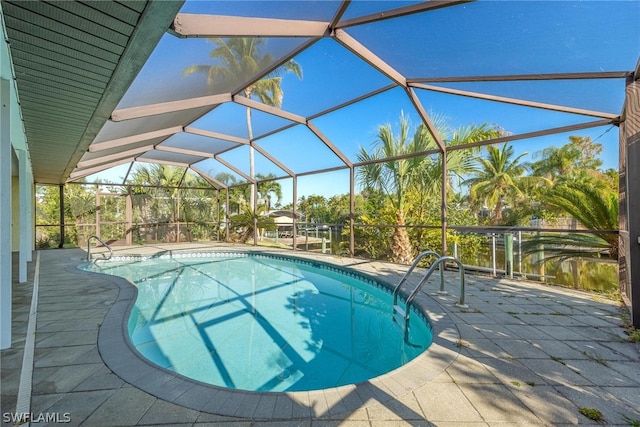 view of pool with glass enclosure, a patio area, and a water view