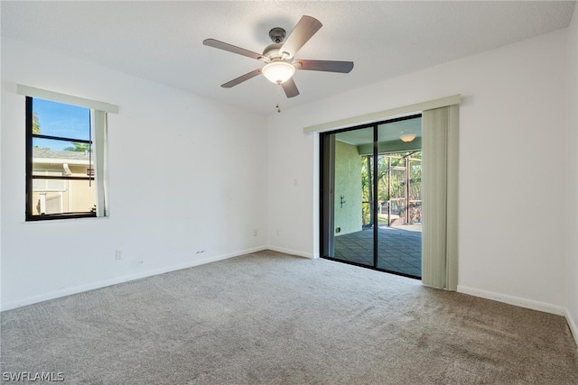 carpeted spare room featuring ceiling fan and a healthy amount of sunlight