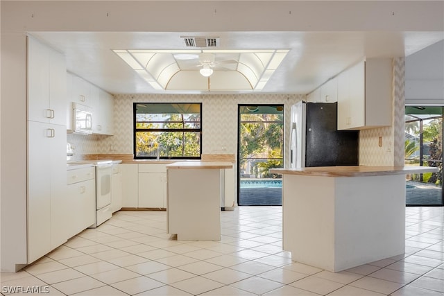 kitchen featuring white cabinets, a wealth of natural light, a kitchen island, and white appliances