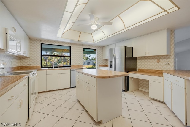 kitchen featuring ceiling fan, white cabinetry, sink, a kitchen island, and appliances with stainless steel finishes