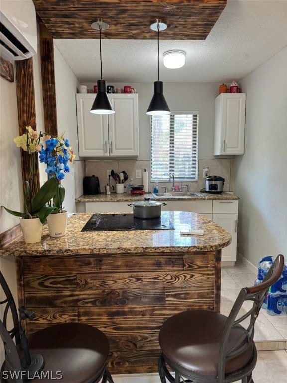 kitchen with tasteful backsplash, light tile patterned floors, white cabinets, light stone countertops, and sink