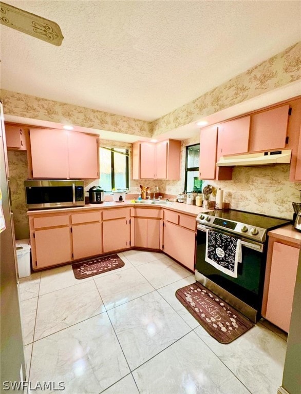 kitchen featuring light tile patterned flooring, light brown cabinets, a textured ceiling, and stainless steel appliances