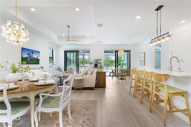 dining room featuring sink, ceiling fan, and a tray ceiling