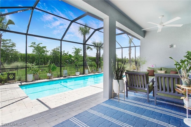 view of swimming pool with an outdoor living space, ceiling fan, glass enclosure, and a patio area