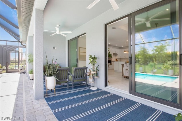 view of patio / terrace featuring ceiling fan and glass enclosure