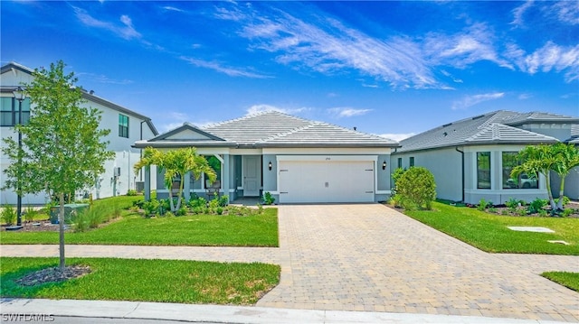 view of front facade with a front yard, a tiled roof, decorative driveway, and an attached garage