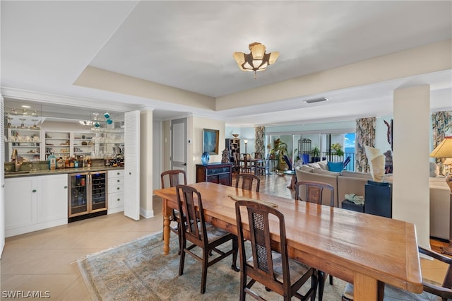 dining space featuring light tile patterned flooring, wet bar, wine cooler, and a tray ceiling