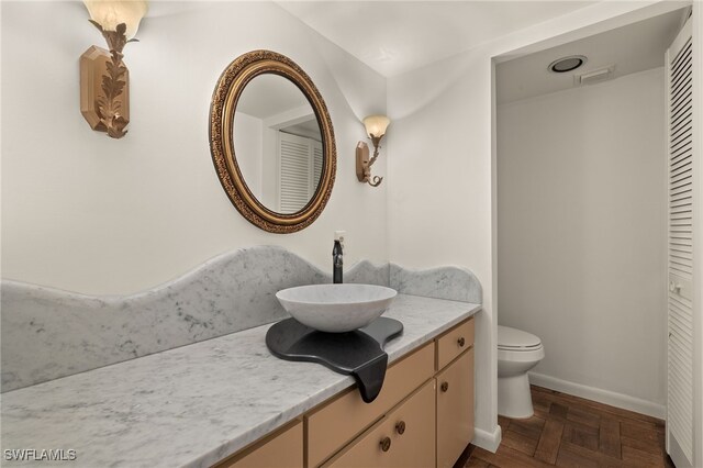 bathroom featuring vanity, toilet, and parquet flooring