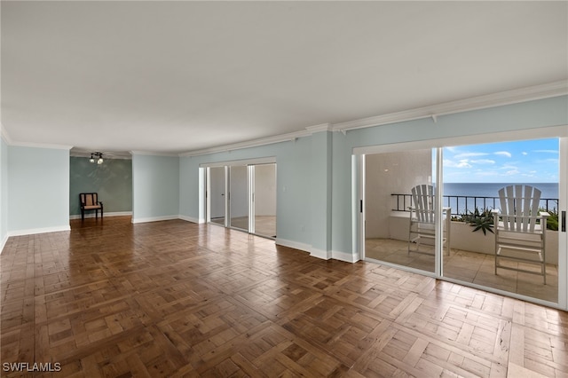 empty room featuring baseboards, a water view, and crown molding