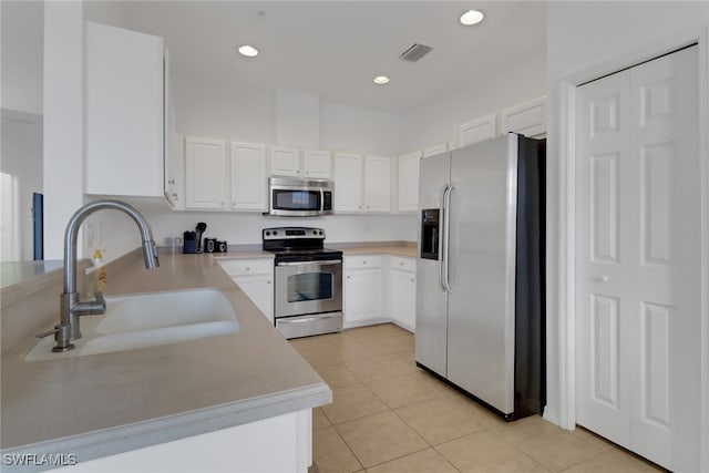 kitchen featuring sink, white cabinets, light tile patterned floors, and appliances with stainless steel finishes