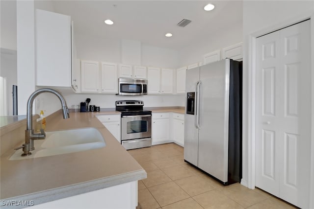 kitchen featuring light tile patterned floors, stainless steel appliances, white cabinetry, and sink