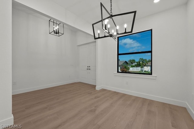 unfurnished dining area featuring an inviting chandelier and light hardwood / wood-style flooring