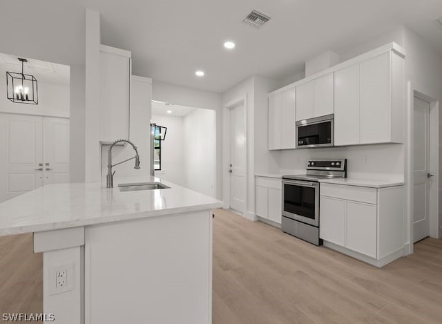 kitchen with sink, light hardwood / wood-style flooring, pendant lighting, and appliances with stainless steel finishes