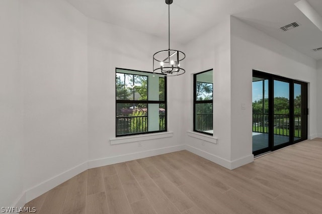 interior space with plenty of natural light, light wood-type flooring, and an inviting chandelier