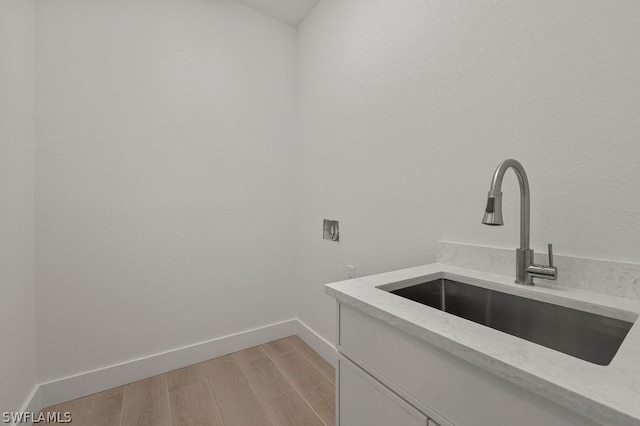 laundry area featuring washer hookup, sink, cabinets, and light hardwood / wood-style flooring