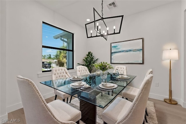 dining space with light hardwood / wood-style floors and a chandelier