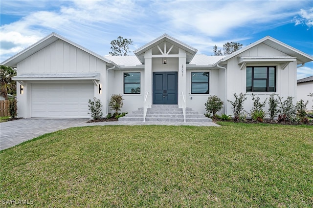 modern farmhouse with a garage, decorative driveway, metal roof, and a front lawn