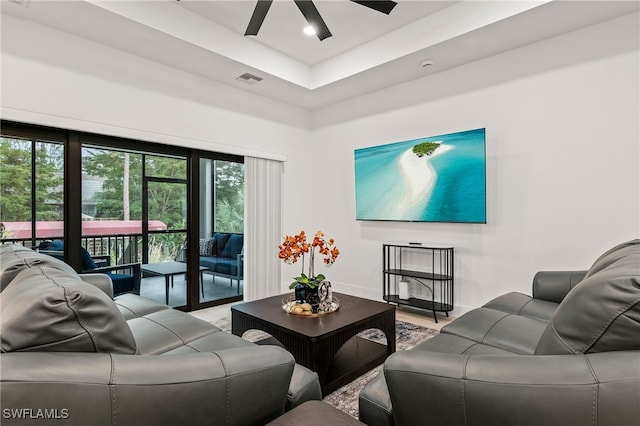 living area with a ceiling fan, visible vents, and baseboards