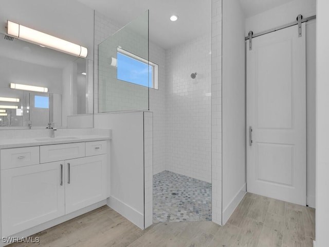 bathroom with tiled shower, vanity, and hardwood / wood-style flooring