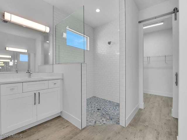 bathroom featuring hardwood / wood-style flooring, a tile shower, and vanity