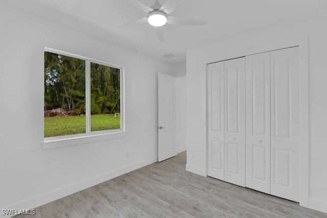 unfurnished bedroom with light wood-type flooring, ceiling fan, and a closet