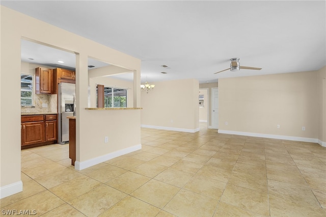 empty room with light tile flooring and ceiling fan with notable chandelier