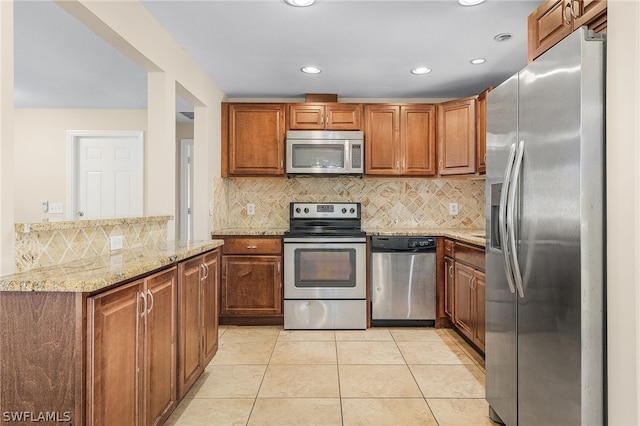 kitchen with light stone counters, tasteful backsplash, light tile floors, and appliances with stainless steel finishes