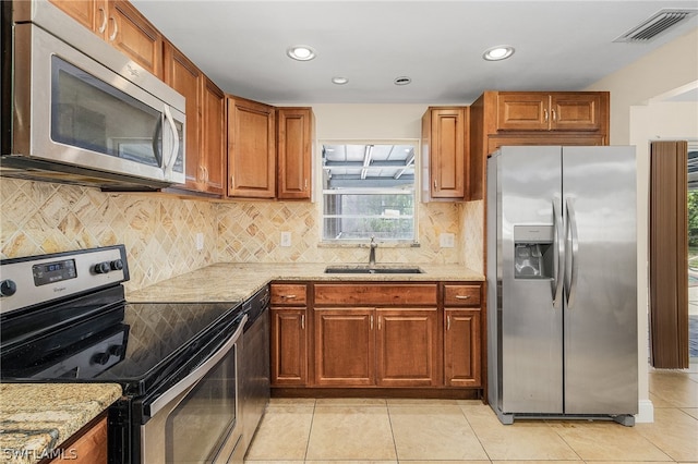 kitchen featuring appliances with stainless steel finishes, sink, tasteful backsplash, and light tile flooring