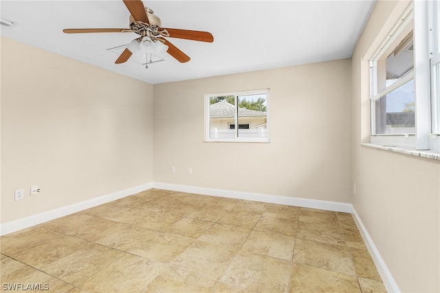 spare room with ceiling fan and light tile floors