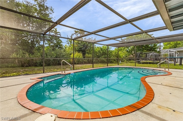 view of pool with glass enclosure and a patio area