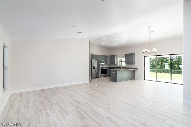 kitchen with high vaulted ceiling, a kitchen breakfast bar, light hardwood / wood-style flooring, stainless steel appliances, and a chandelier