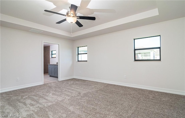 carpeted spare room featuring ceiling fan and a raised ceiling